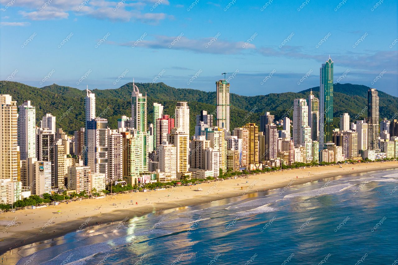 Balneário Camboriú, Santa Catarina, vista diurna com edifícios modernos refletindo luz do sol e montanhas ao fundo
