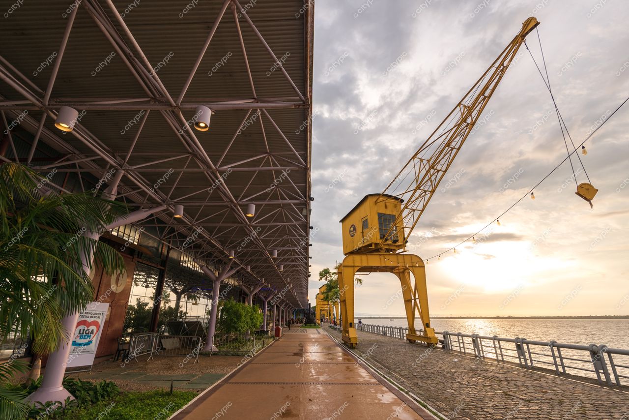 Belém, Pará apresenta o espaço portuário ao amanhecer com grua amarela e vegetação tropical emoldurando a cena