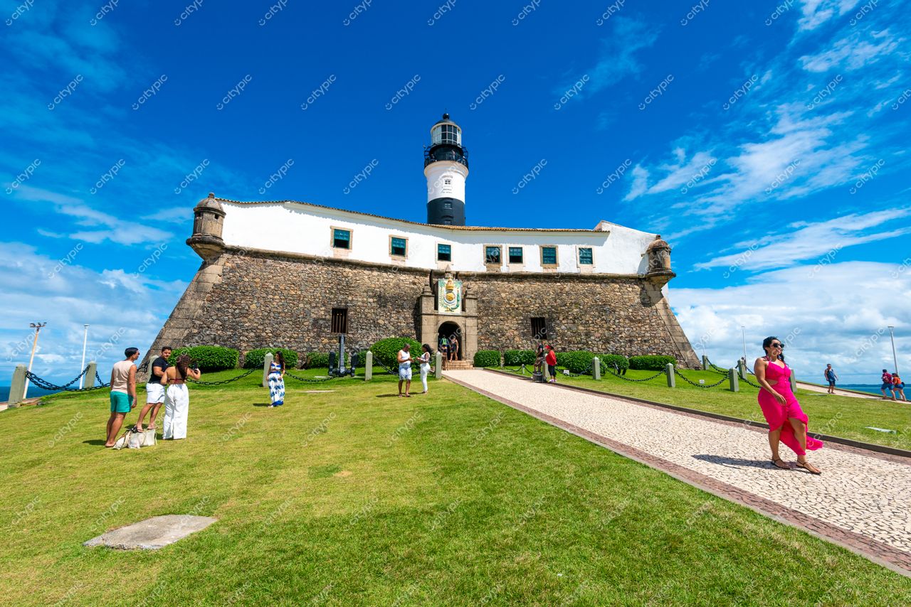 Salvador, Bahia, Farol da Barra em dia ensolarado com pessoas no gramado e céu azul claro