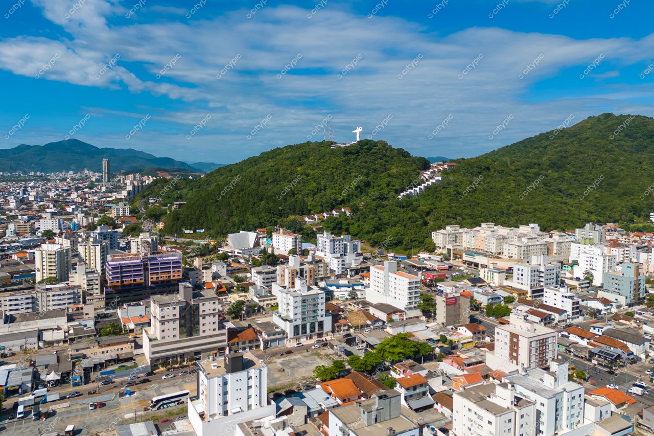 Balneário Camboriú, Santa Catarina vista aérea com morro verde, escadaria visível e tráfego discreto em dia ensolarado