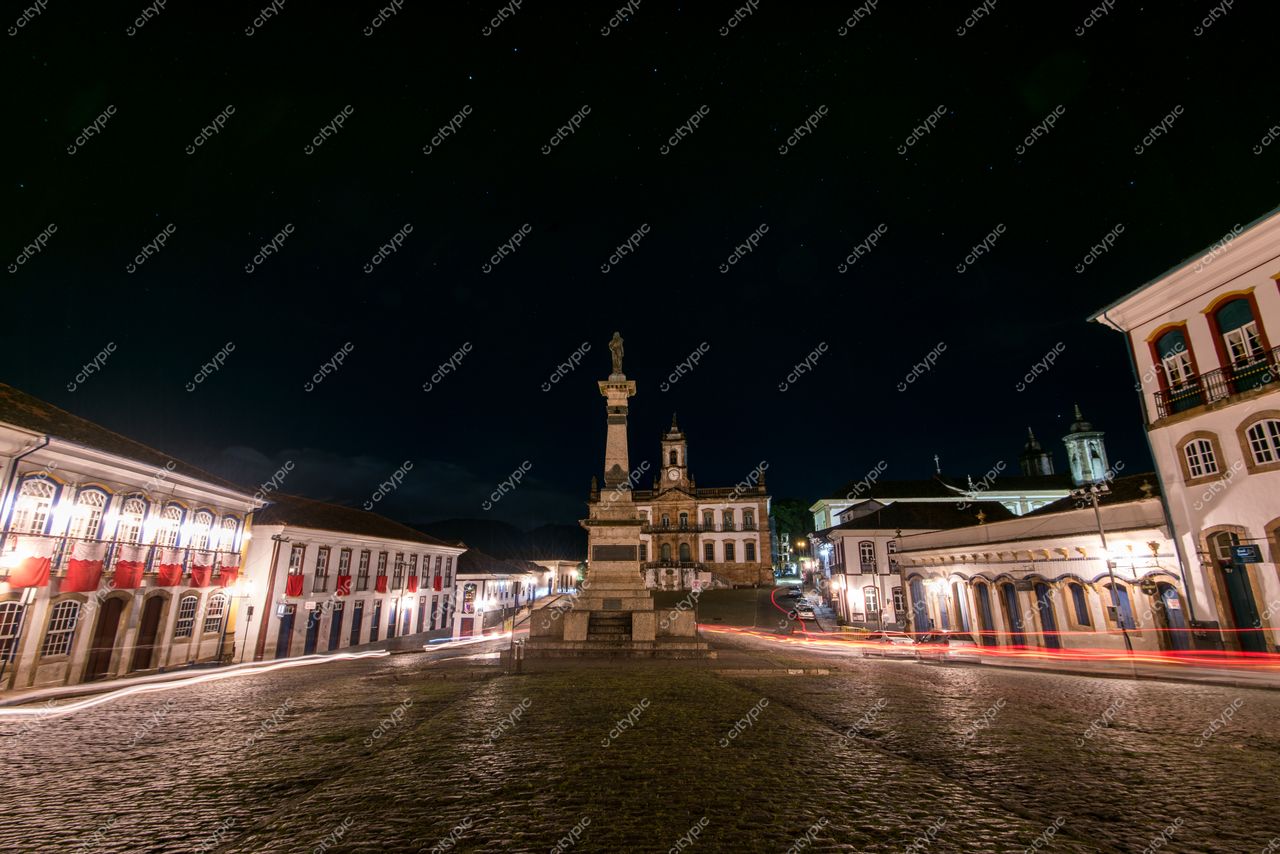 Ouro Preto, Minas Gerais à noite com monumento central iluminado e edifícios coloniais coloridos na Praça Tiradentes