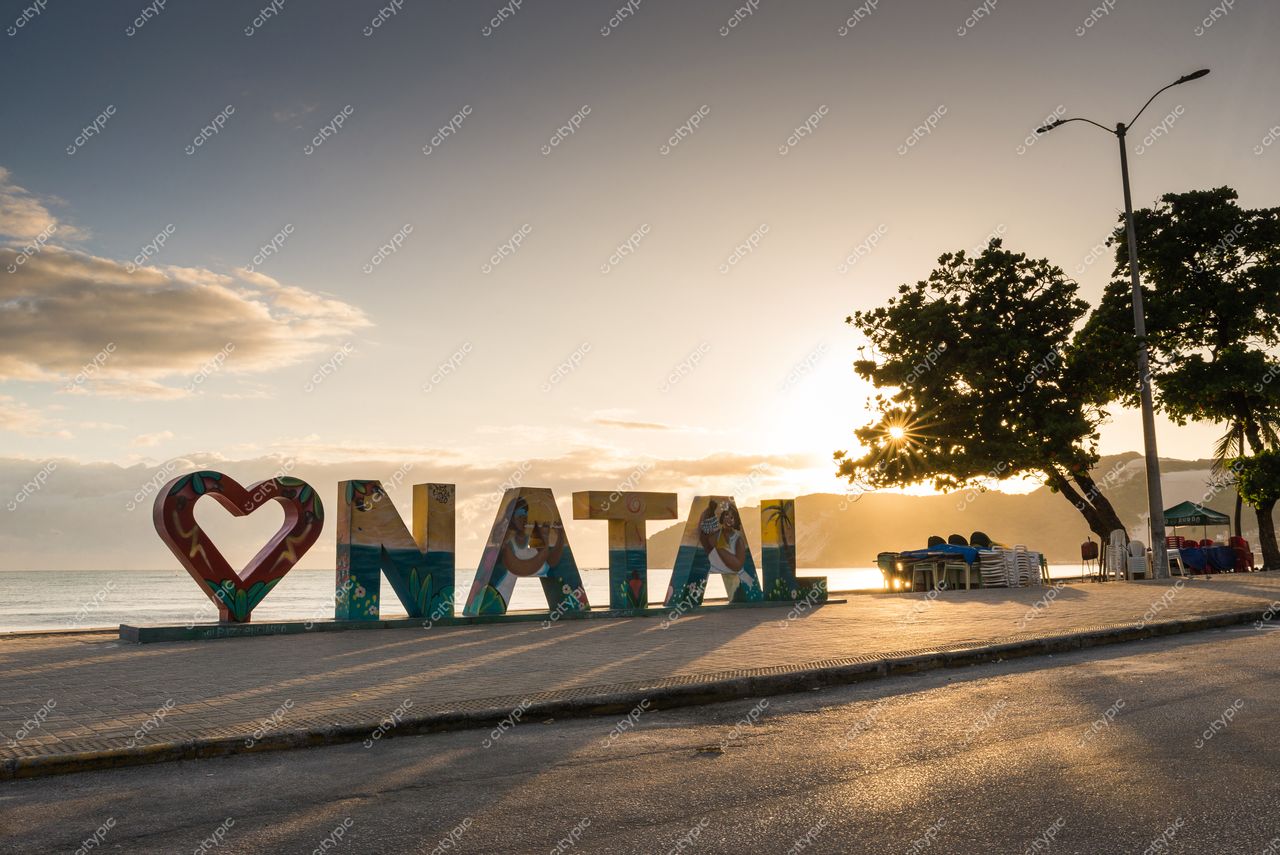 Natal, Rio Grande do Norte ao amanhecer com letreiro “I ❤️ NATAL” e mar refletindo tons quentes do céu