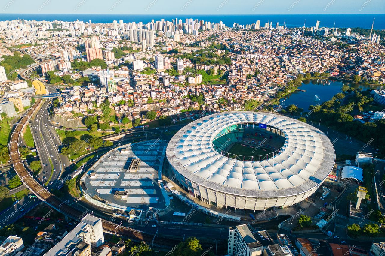 Salvador, Bahia vista aérea do Estádio Fonte Nova com arquitetura moderna e relevo urbano ao fundo em luz diurna