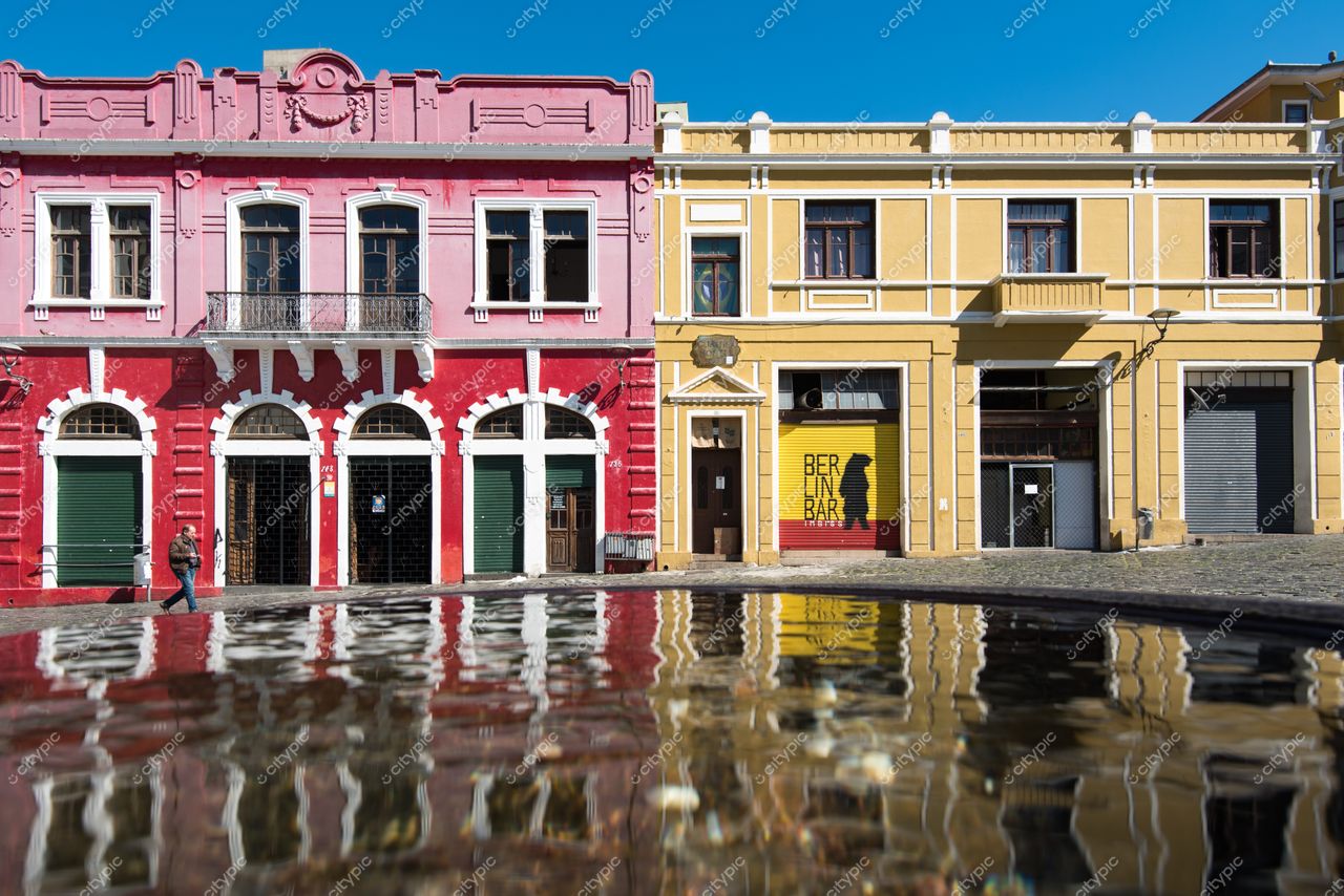 Curitiba, Paraná, fachadas coloridas de construções históricas em dia ensolarado com reflexo na água e rua vazia