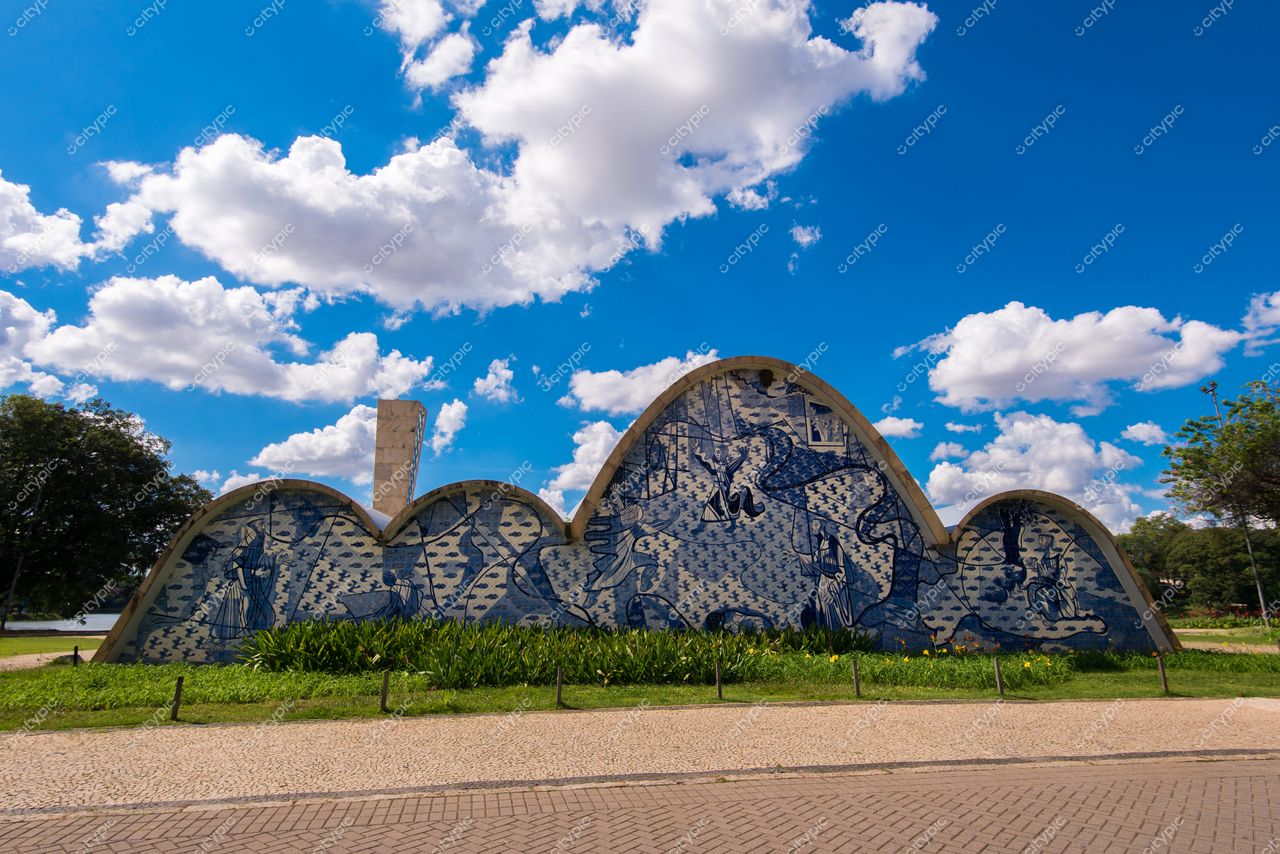 Belo Horizonte, Minas Gerais, edifício em forma de ondas com mural azul e branco sob céu nublado e vegetação cuidada