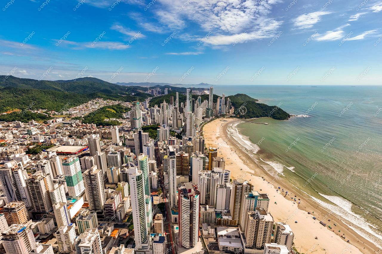 Balneário Camboriú, Santa Catarina, vista aérea com arranha-céus modernos e vegetação densa sob céu ensolarado