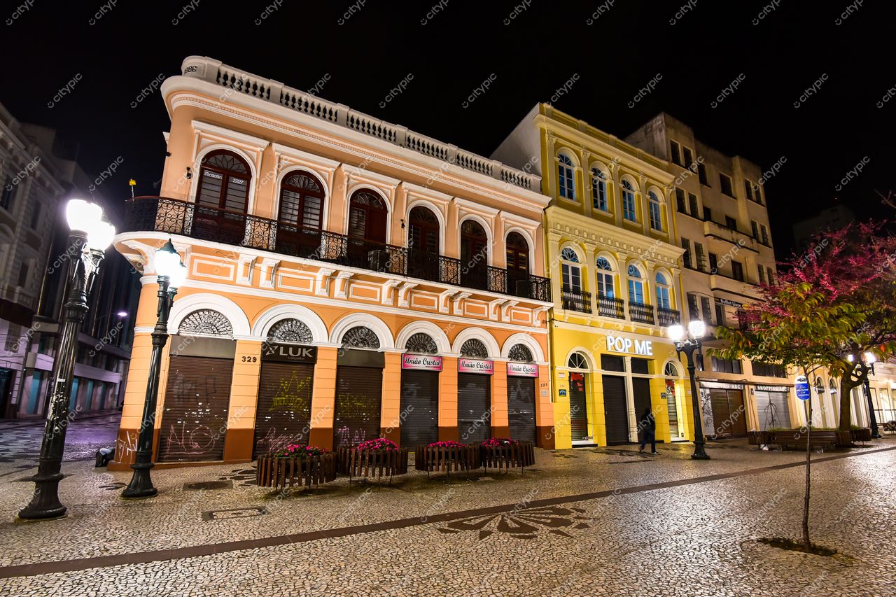 Curitiba, Paraná, rua histórica à noite com edifícios coloridos e iluminação suave em calçada de pedras portuguesas