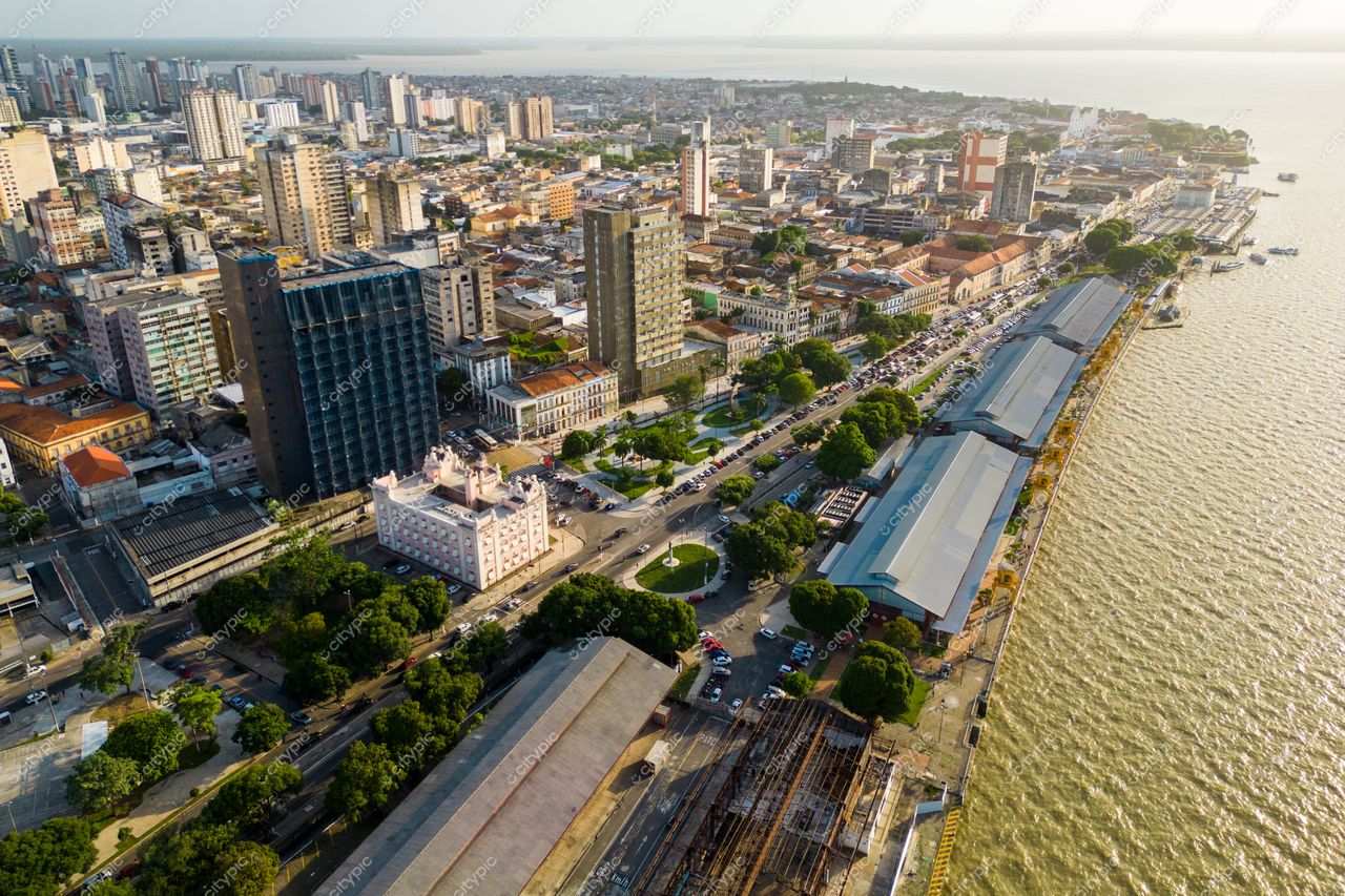 Belém, Pará com vista aérea do horizonte urbano ao entardecer destacando a vegetação e o tráfego na orla