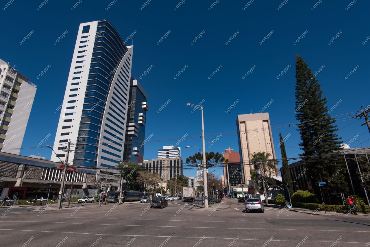 Curitiba, Paraná, cenário urbano com prédios modernos, céu azul e tráfego intenso em dia ensolarado