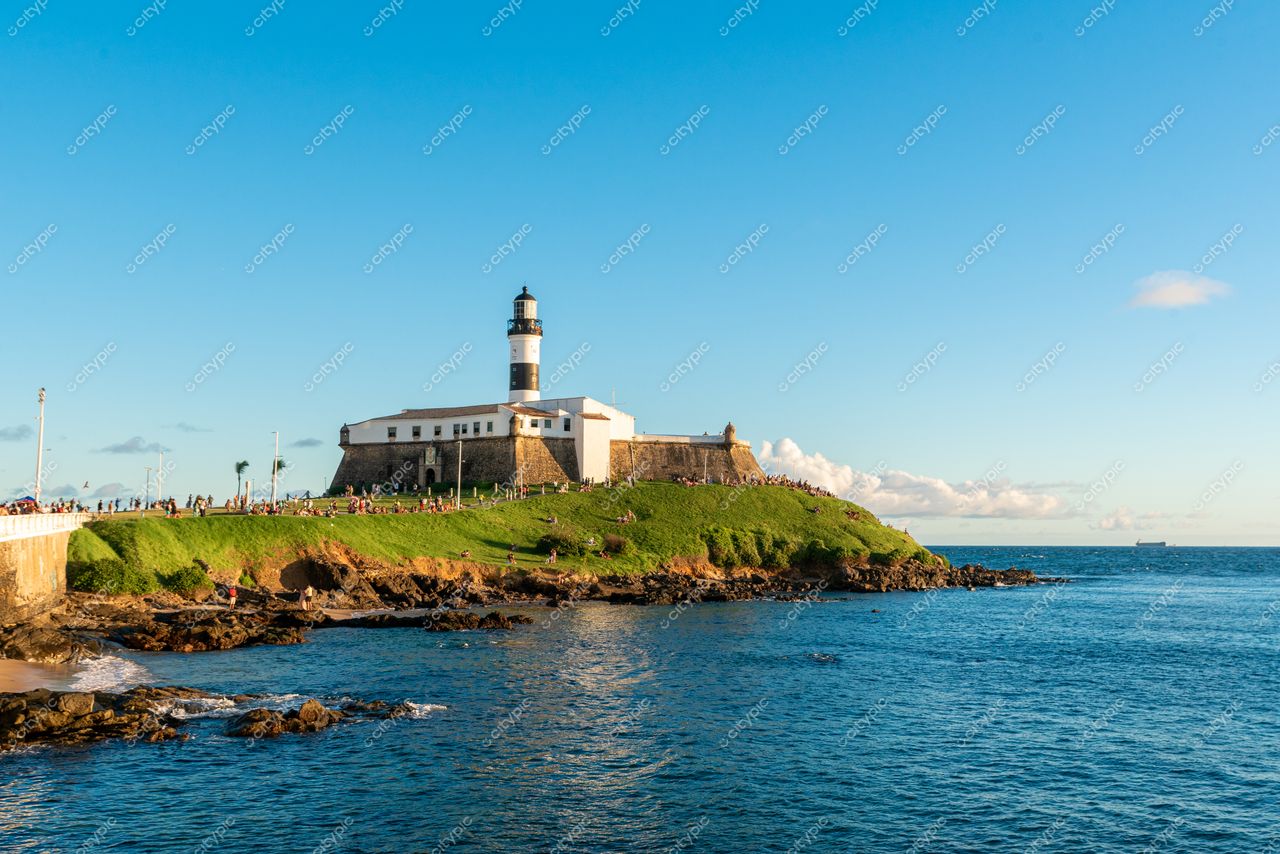 Salvador, Bahia, Farol da Barra em dia ensolarado com vegetação verdejante e mar calmo ao fundo