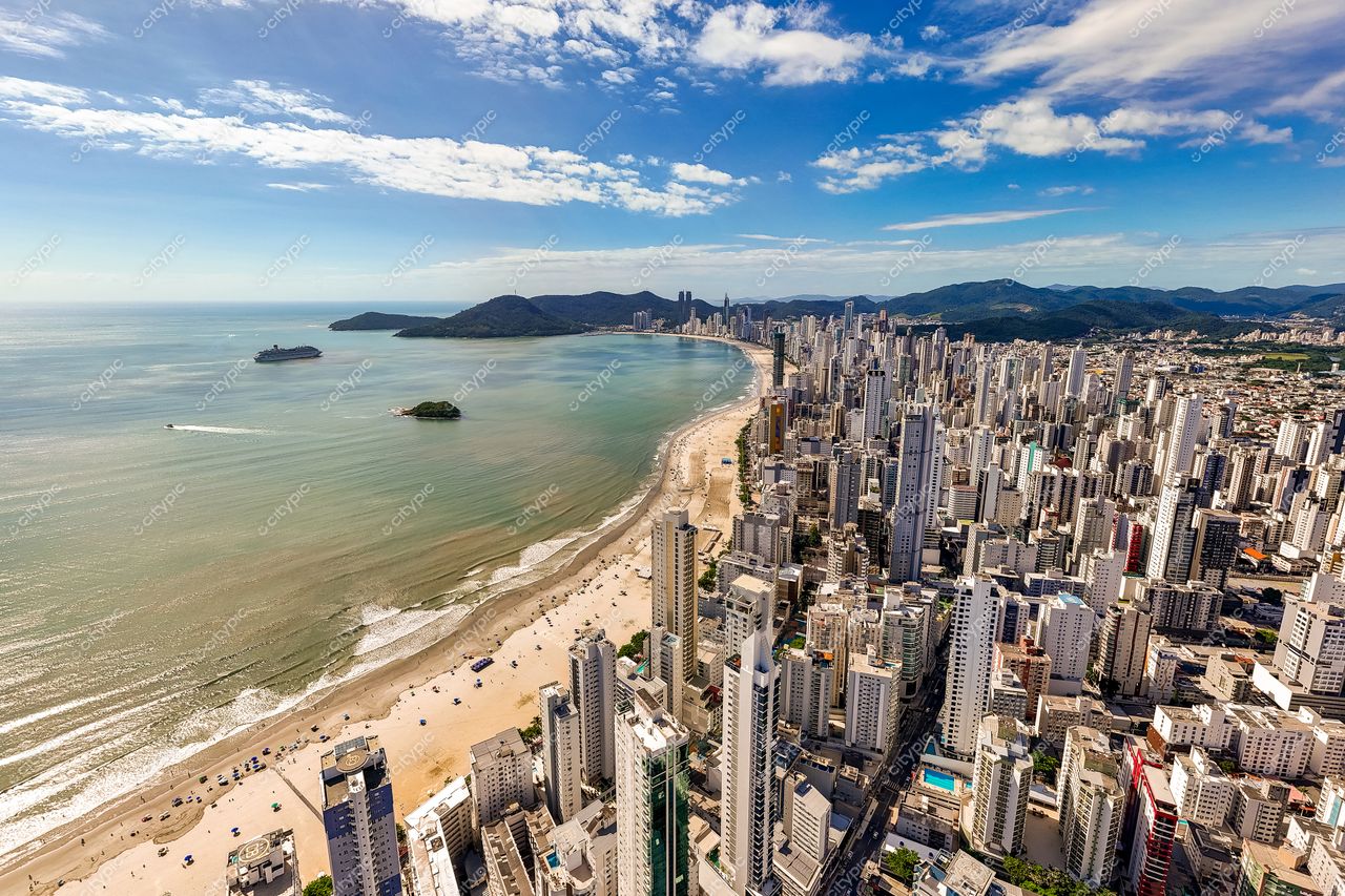 Balneário Camboriú, Santa Catarina vista panorâmica com arranha-céus, praia, céu azul e vegetação montanhosa ao fundo