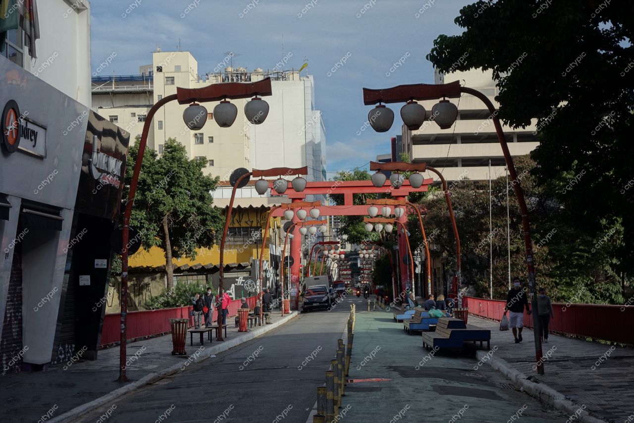Liberdade em São Paulo com ruas arborizadas, estruturas vermelhas e iluminação suave em um dia claro