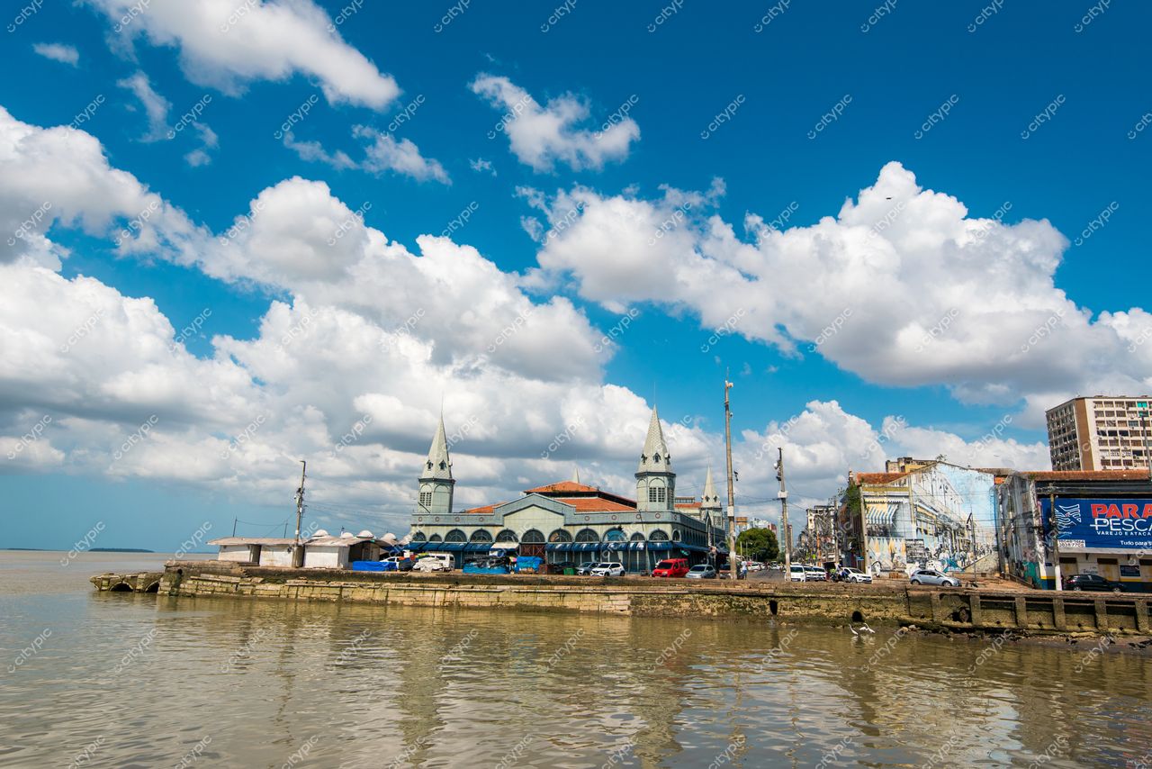 Belém, Pará com céu azul claro e nuvens brancas destaca edifício clássico à beira de corpo d’água calmo