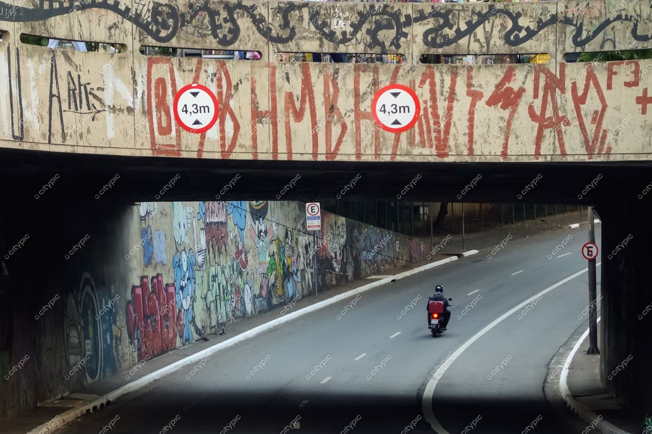 São Paulo, São Paulo, túnel urbano com grafites coloridos e motocicleta em movimento sob luz natural diurna