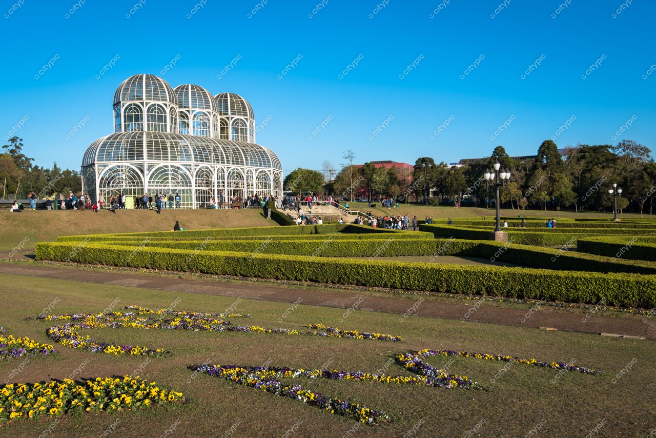Curitiba, Paraná, Jardim Botânico com estufa de vidro em dia ensolarado e visitantes no gramado florido
