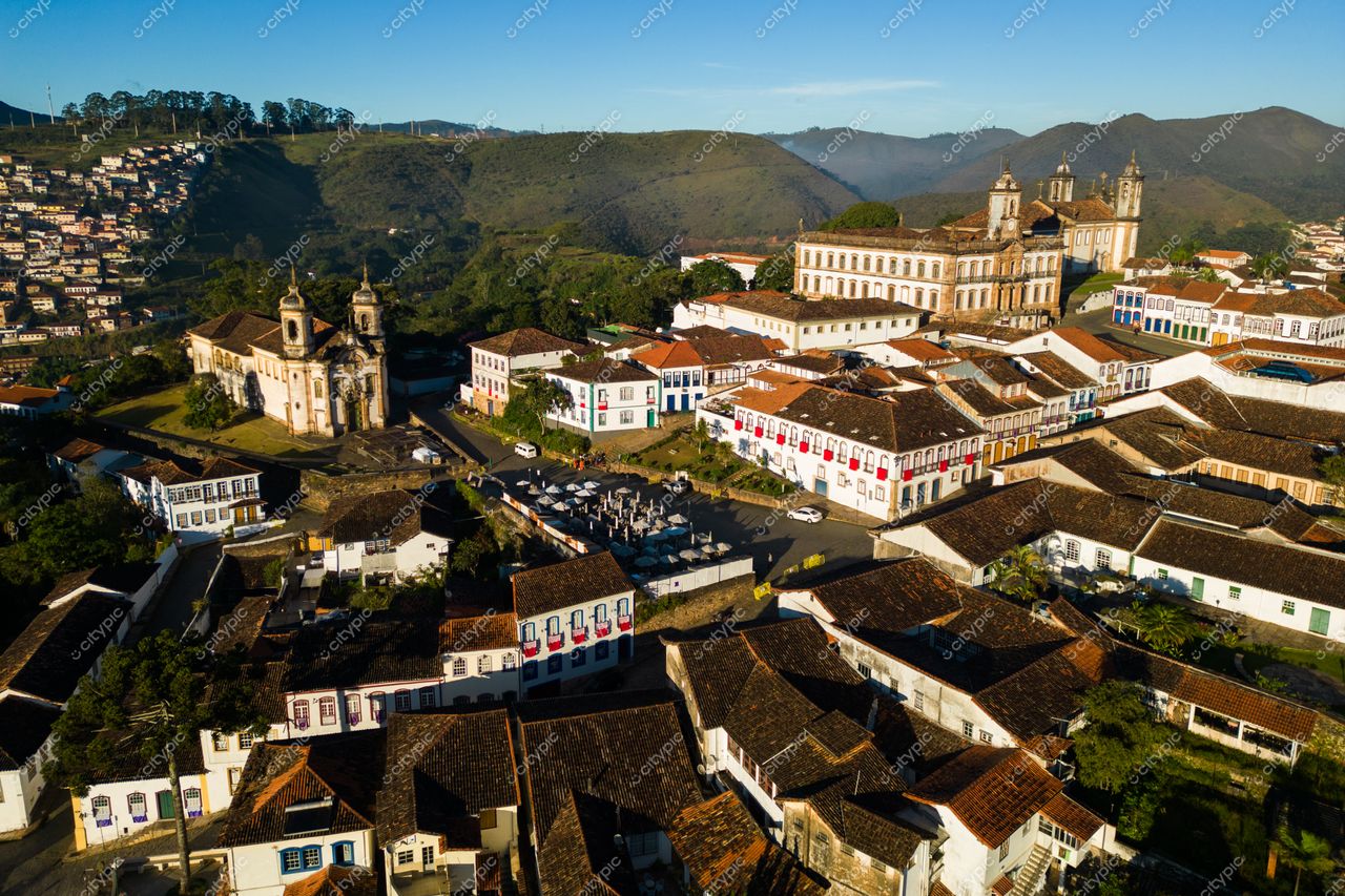 Ouro Preto, Minas Gerais vista aérea ao amanhecer com arquitetura colonial, vegetação exuberante e movimentação na praça central