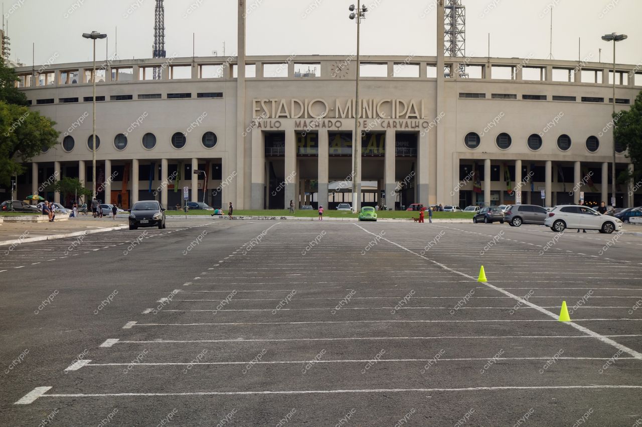Estádio do Pacaembu em São Paulo com fachada iluminada ao entardecer e estacionamento vazio em primeiro plano