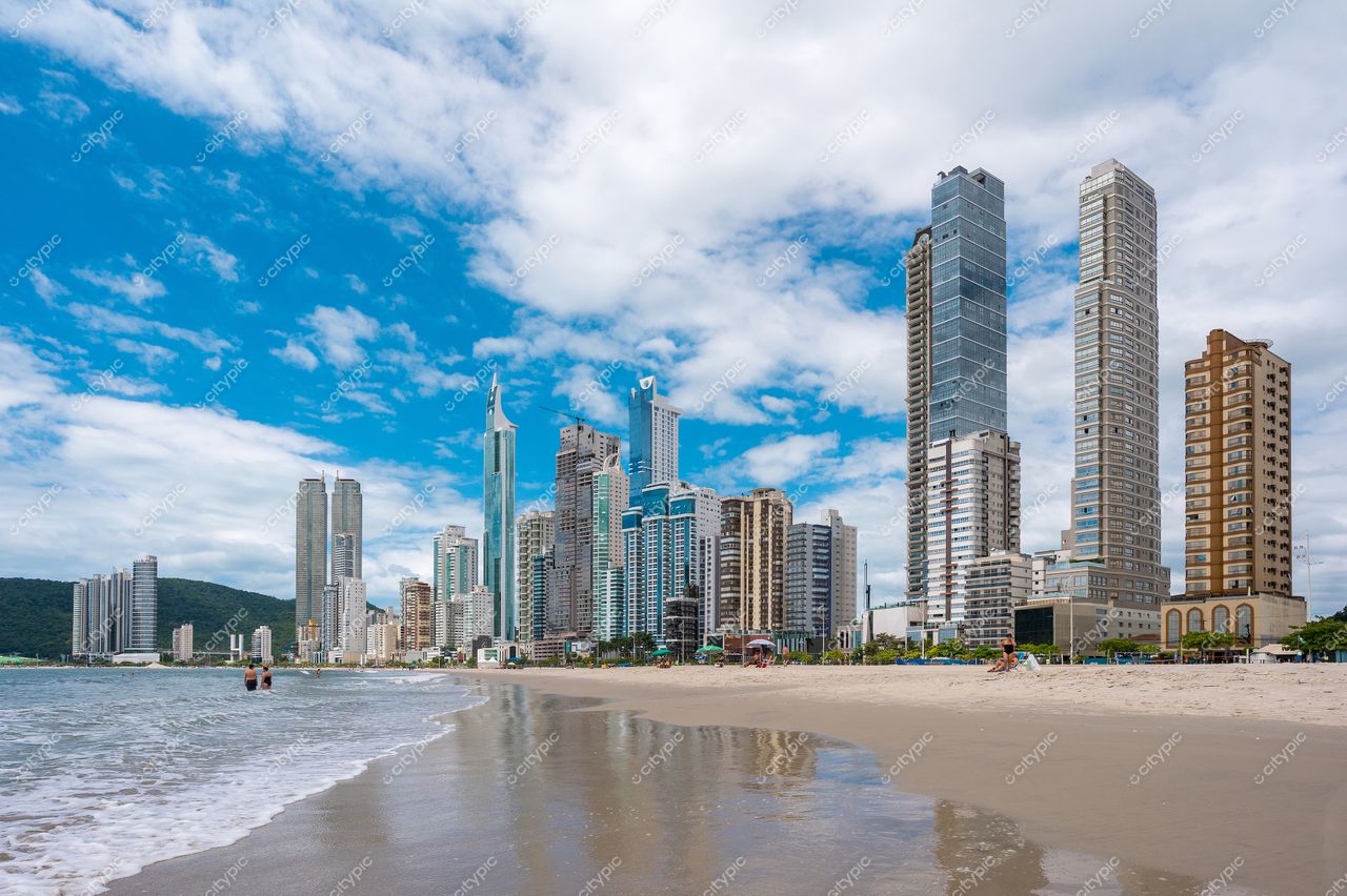 Balneário Camboriú, Santa Catarina, orla com arranha-céus modernos sob céu azul em dia ensolarado e vegetação ao fundo