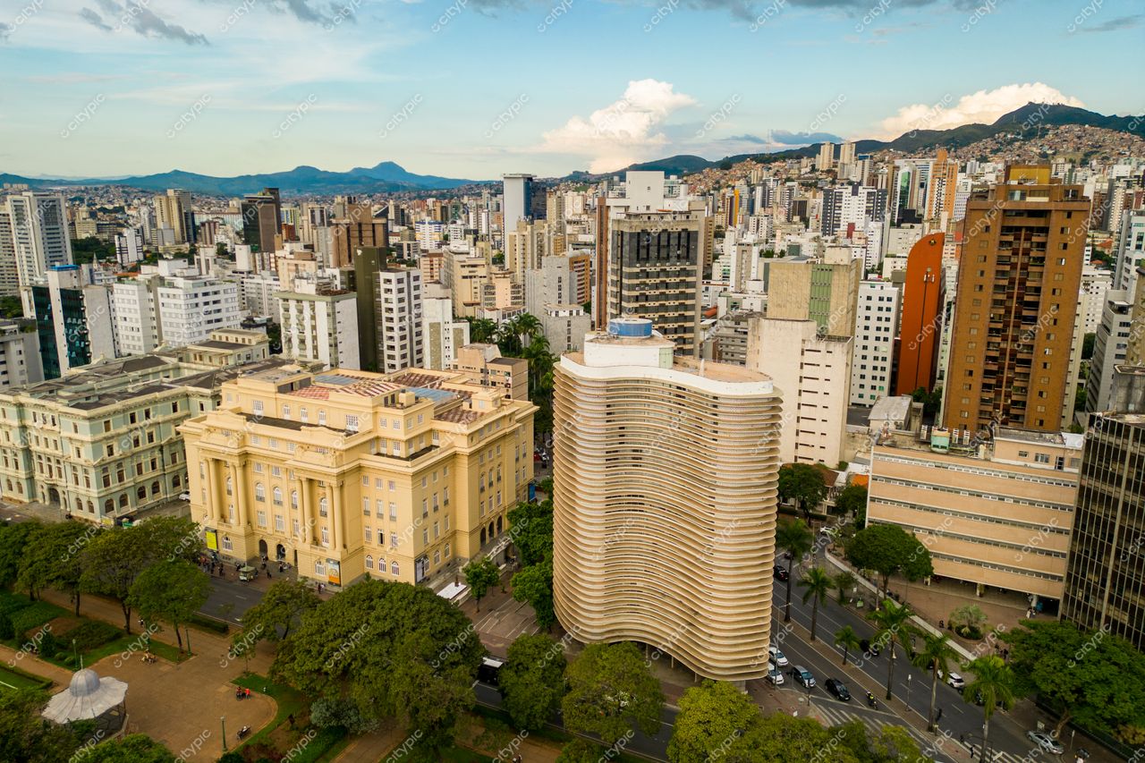 Belo Horizonte, Minas Gerais, vista panorâmica com prédios variados e construção ondulada ao entardecer sob céu nublado