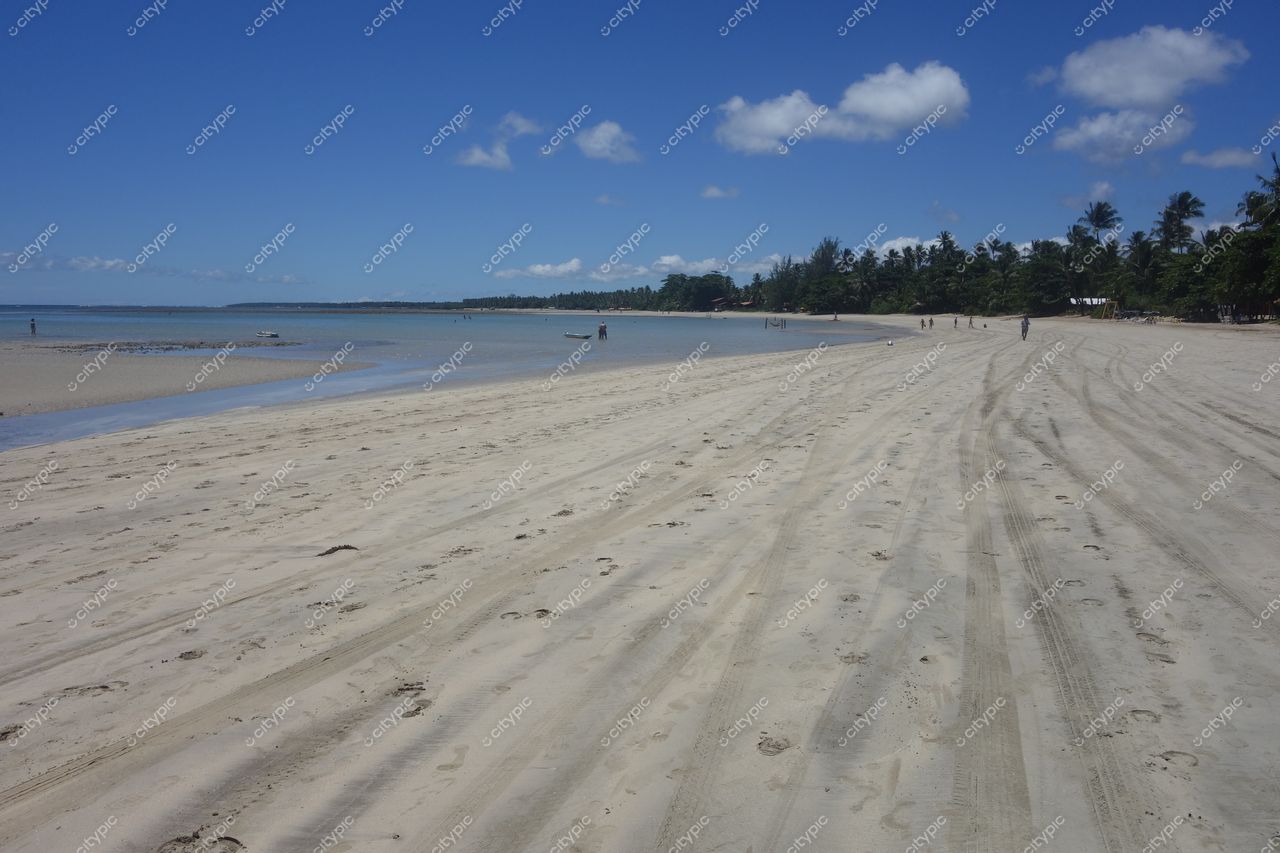 Morro de São Paulo, Bahia com praia de areia clara, vegetação tropical e pessoas caminhando sob céu parcialmente nublado