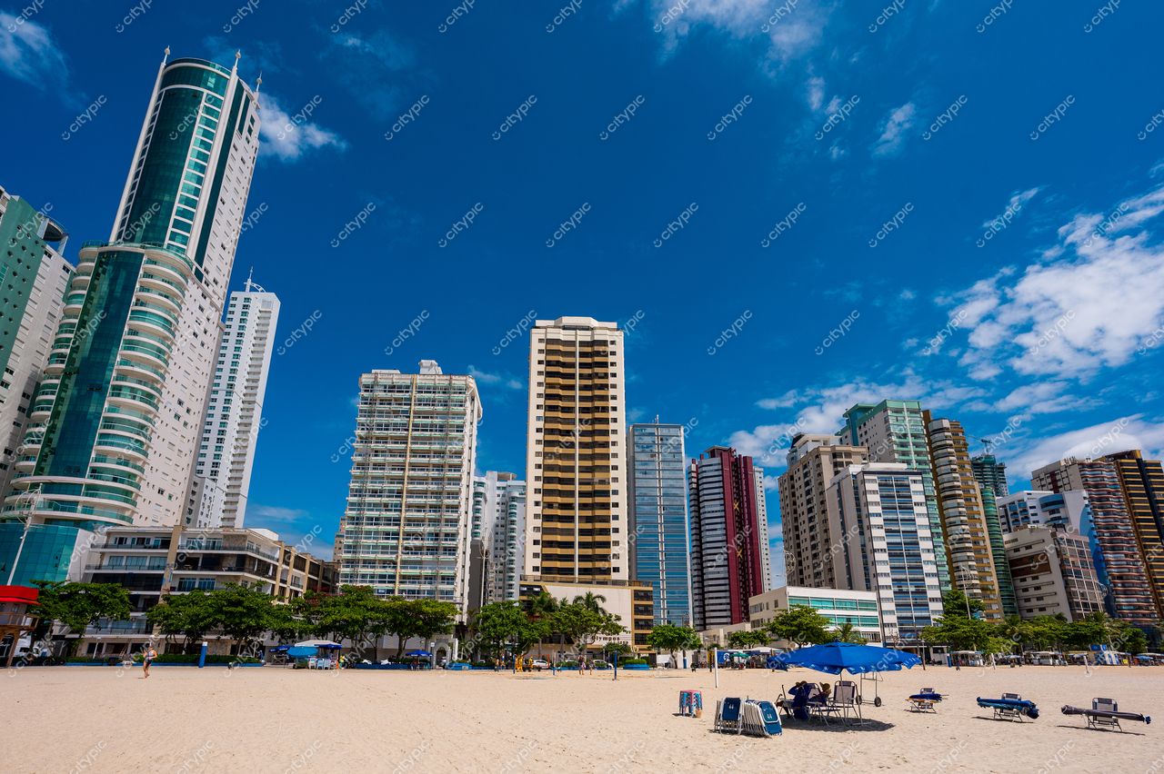 Balneário Camboriú, Santa Catarina, vista da praia com arranha-céus modernos e sombras de árvores ao fundo