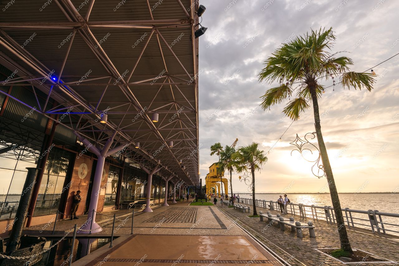 Belém, Pará, promenade à beira-mar com estrutura metálica ao fundo e luz suave do pôr do sol refletindo na água