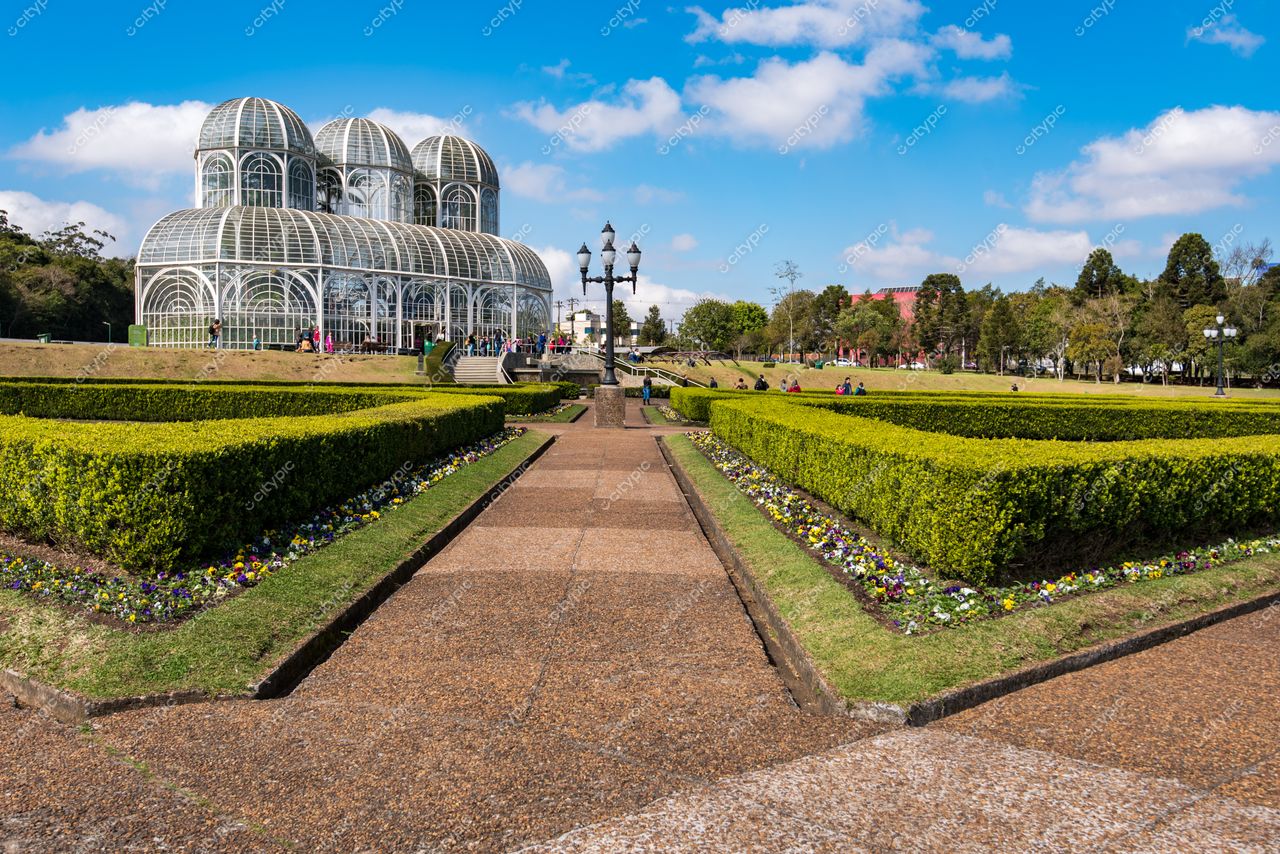 Curitiba, Paraná, Jardim Botânico com estufa de vidro ao fundo e visitantes em dia ensolarado entre flores coloridas