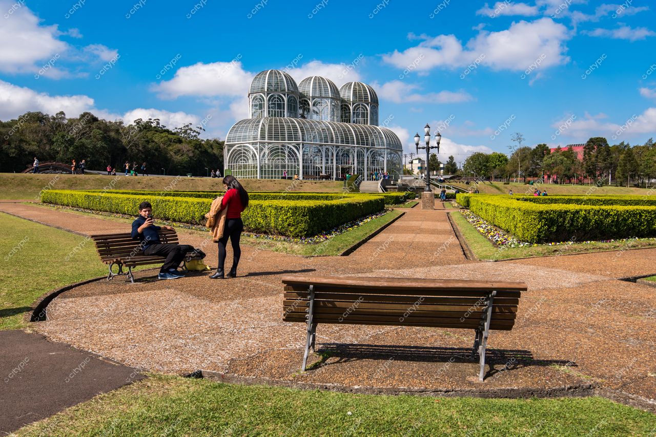 Curitiba, Paraná vista do Jardim Botânico com estufa de vidro e bancos de madeira em dia ensolarado