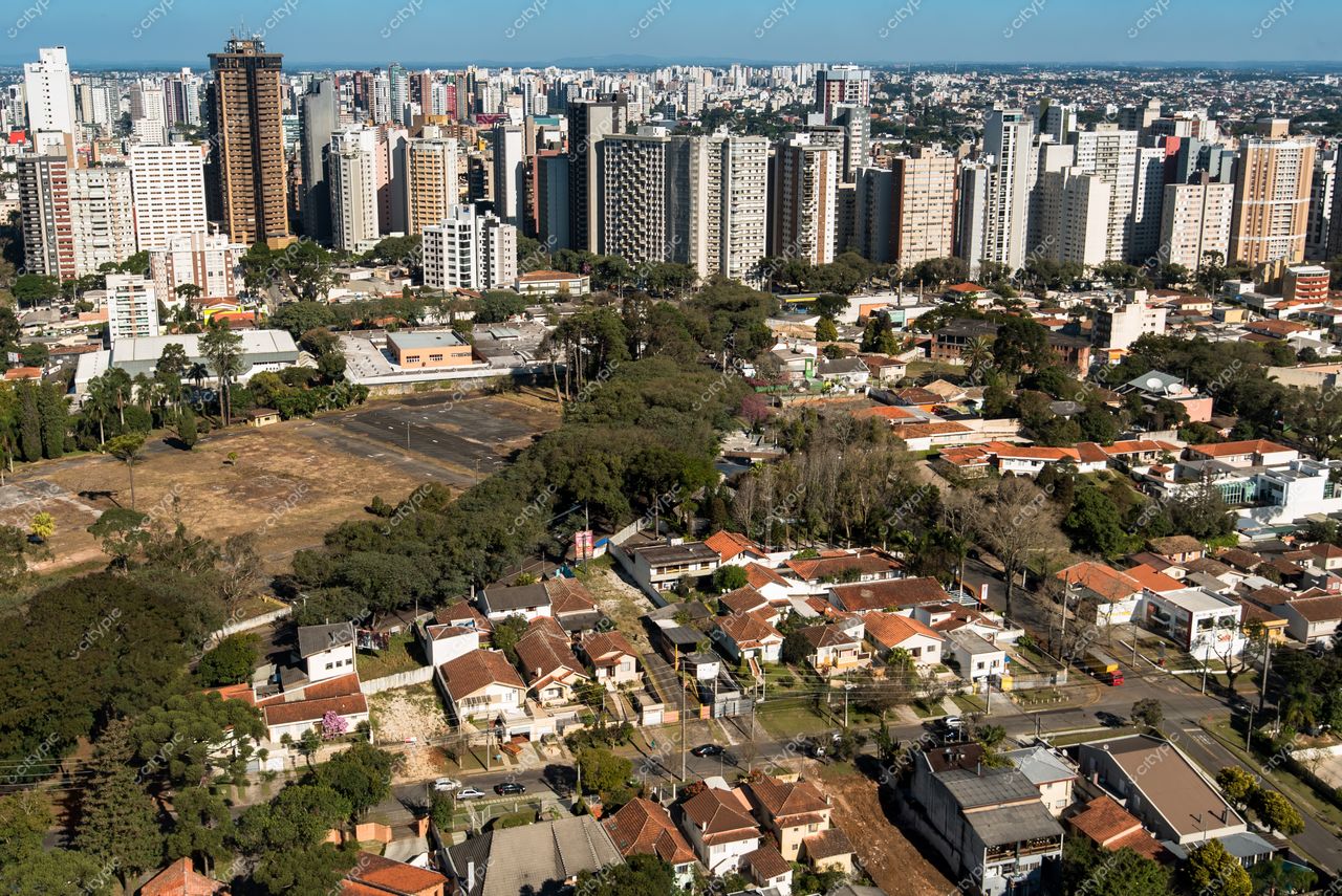 Curitiba, Paraná vista panorâmica com casas de telhados vermelhos e edifícios altos sob luz solar intensa