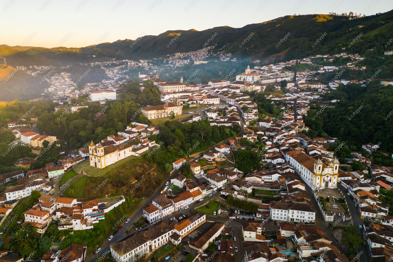 Ouro Preto, Minas Gerais vista aérea ao amanhecer com telhados de barro e montanhas ao fundo em meio à vegetação