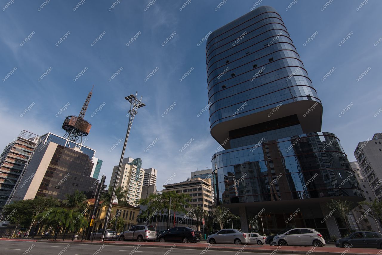 São Paulo, São Paulo, edifício de vidro refletindo o céu claro com torre de comunicação ao fundo e palmeiras