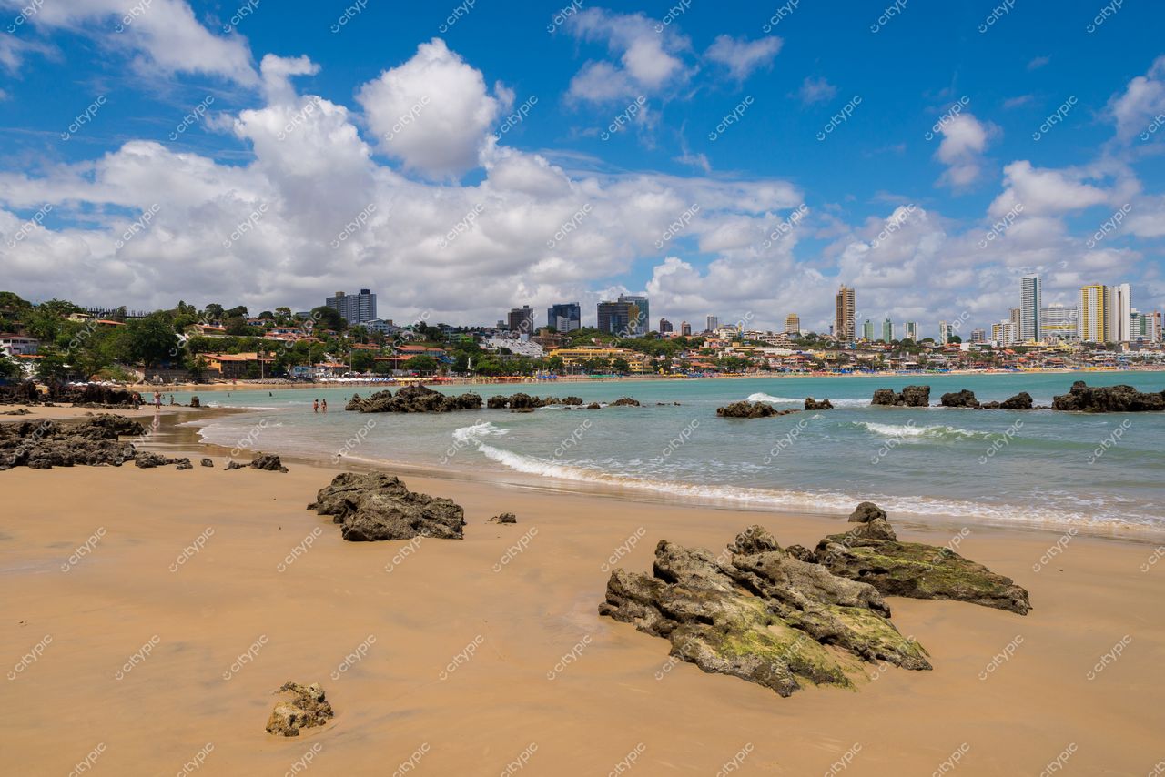 Natal, Rio Grande do Norte, praia com areias claras e rochas, cidade em desenvolvimento ao fundo sob céu azul