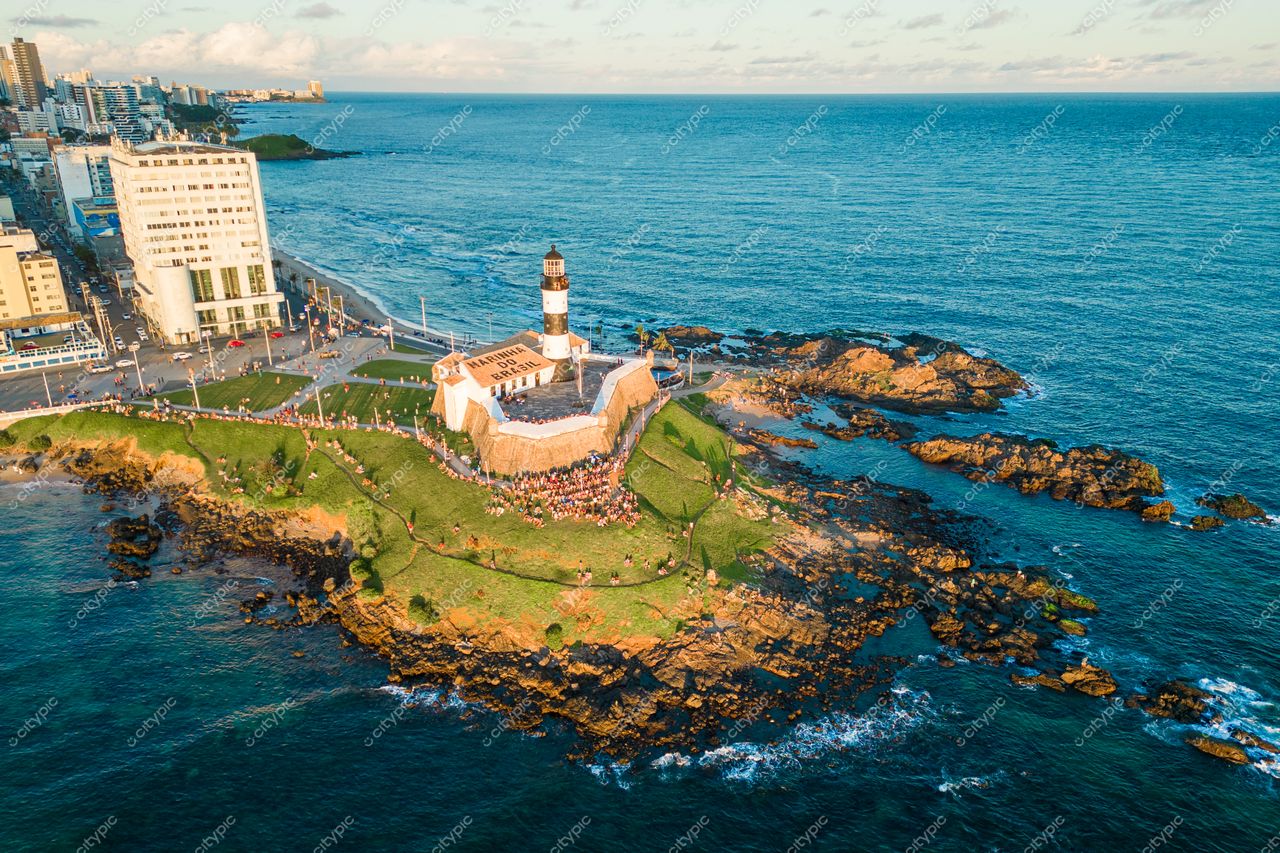 Salvador, Bahia, Farol da Barra ao entardecer com mar azul, edifícios urbanos e pessoas aproveitando a vista