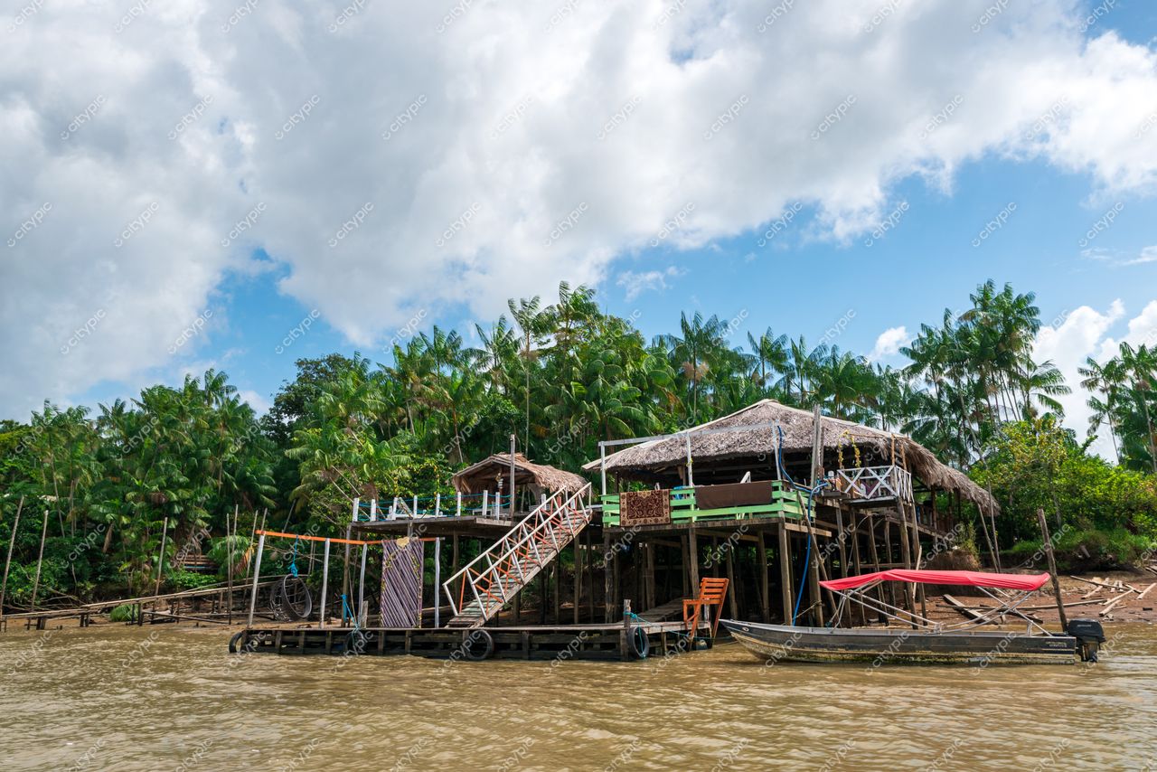 Belém, Pará, construção em palafitas à beira do rio com vegetação densa e canoa amarrada ao lado