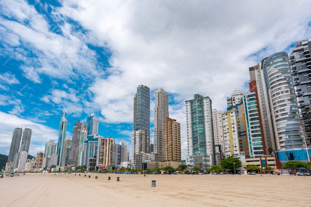 Balneário Camboriú, Santa Catarina com arranha-céus modernos e praia vazia sob céu iluminado e nuvens dispersas