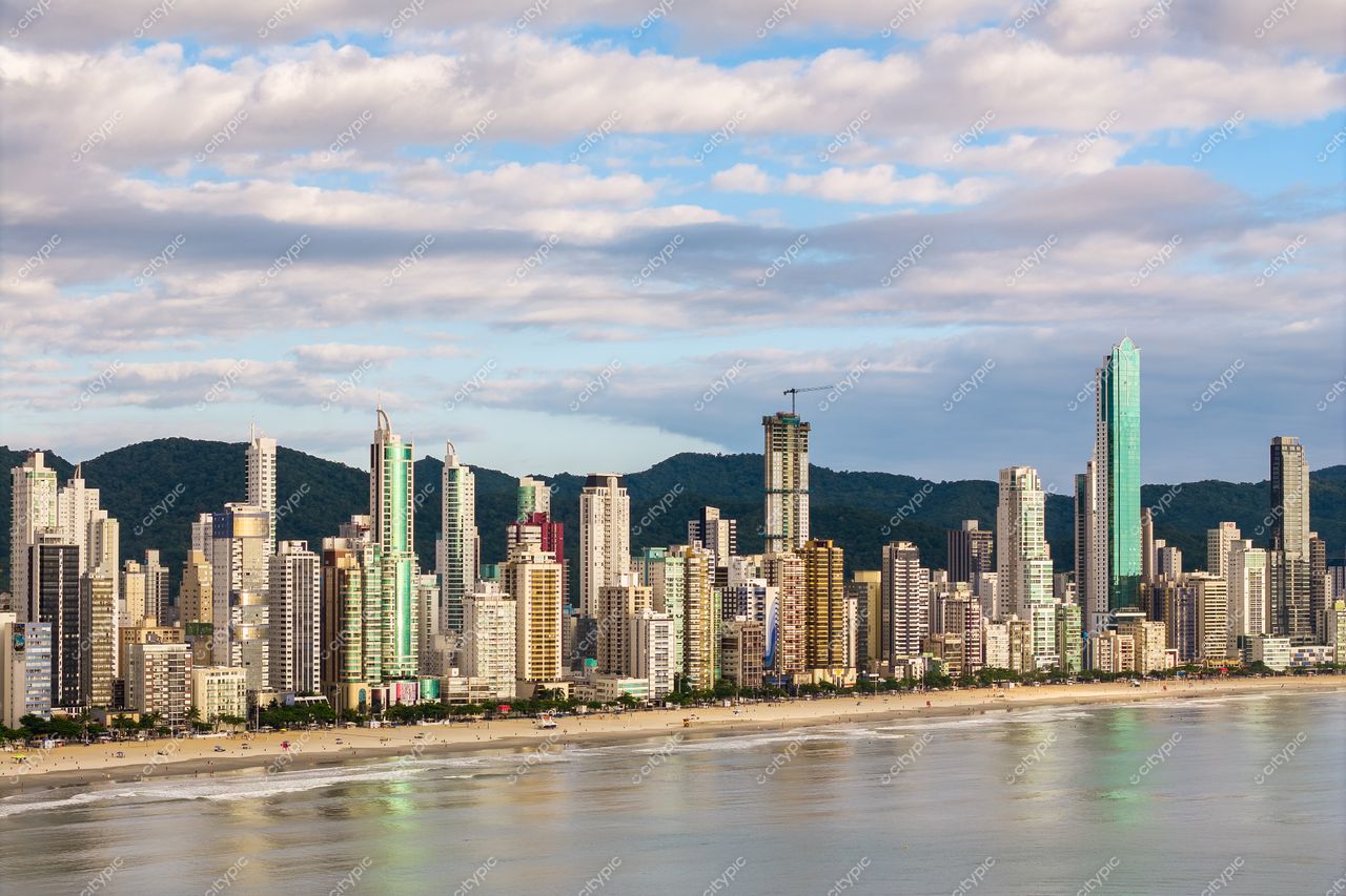 Balneário Camboriú, Santa Catarina, vista urbana com arranha-céus coloridos e montanhas ao fundo em dia nublado