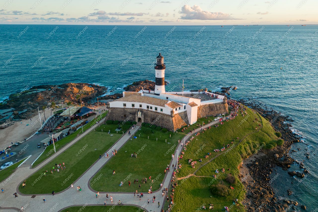Salvador, Bahia vista aérea do Farol da Barra ao entardecer com pessoas caminhando e vegetação ao redor
