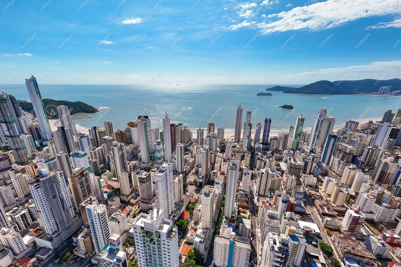 Balneário Camboriú, Santa Catarina, vista panorâmica com arranha-céus e mar refletindo céu claro em dia ensolarado