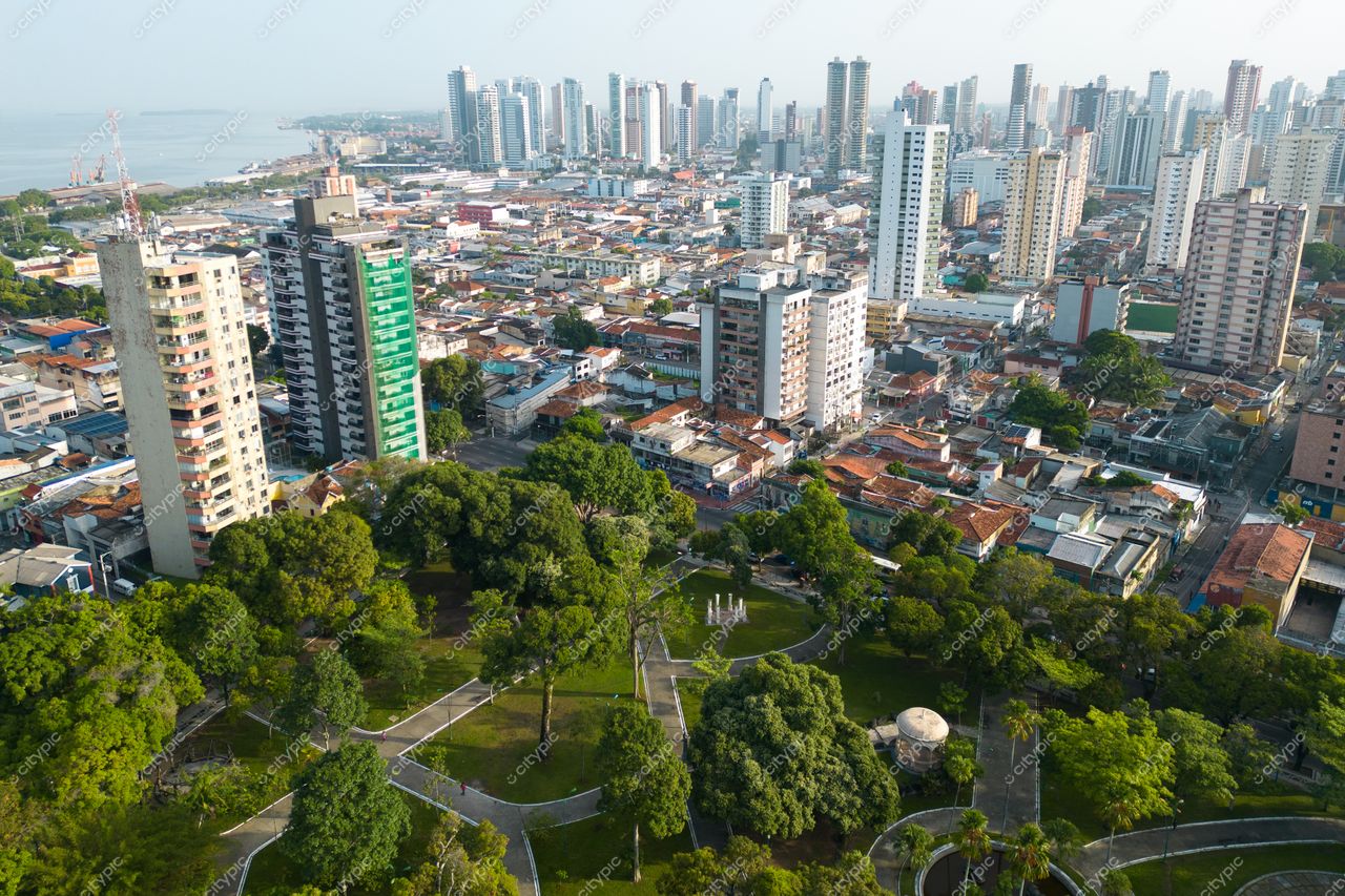 Belém, Pará vista aérea com áreas urbanas e vegetação, edifícios altos ao fundo e céu claro em dia ensolarado