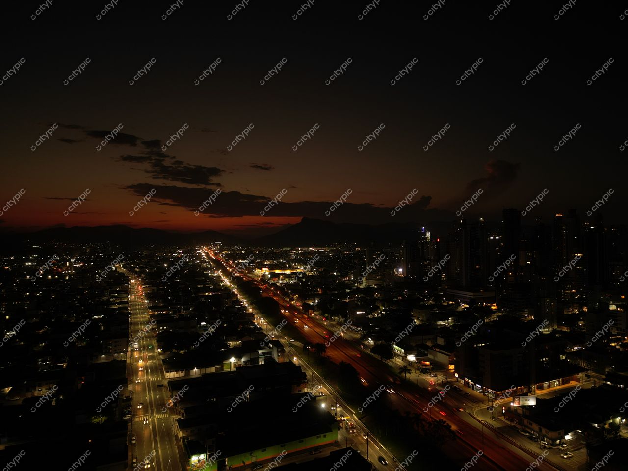 BR-101 em Balneário Camboriú com vista noturna, tráfego leve e edifícios