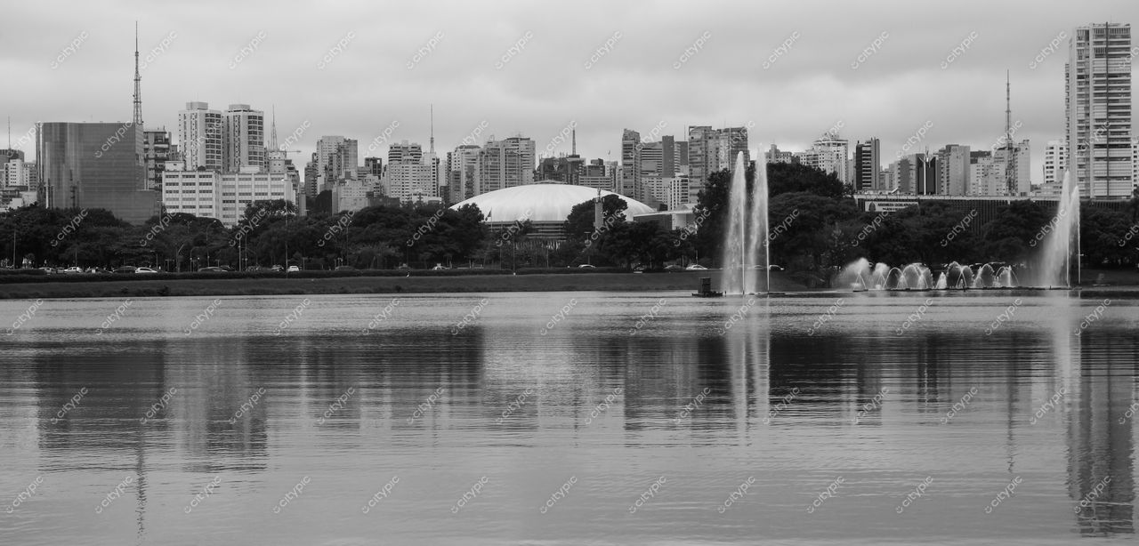 São Paulo, São Paulo, horizonte refletido em lago com edifícios altos e vegetação em dia nublado