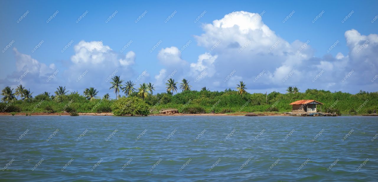 Brejo Grande, Sergipe vista tranquila com águas calmas refletindo céu azul e casarão rústico cercado por vegetação densa