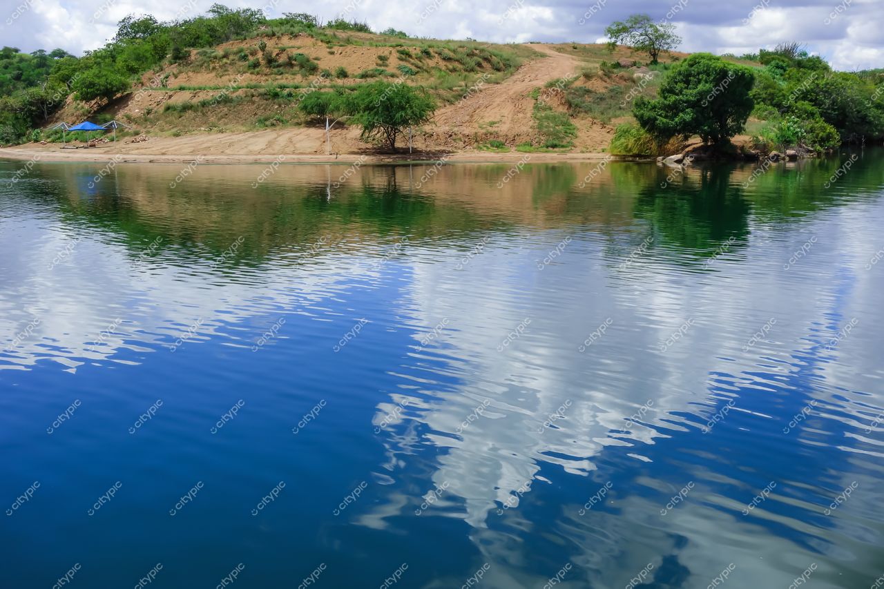Canindé de São Francisco, Sergipe, paisagem tranquila com rio refletindo nuvens e vegetação em relevo suave