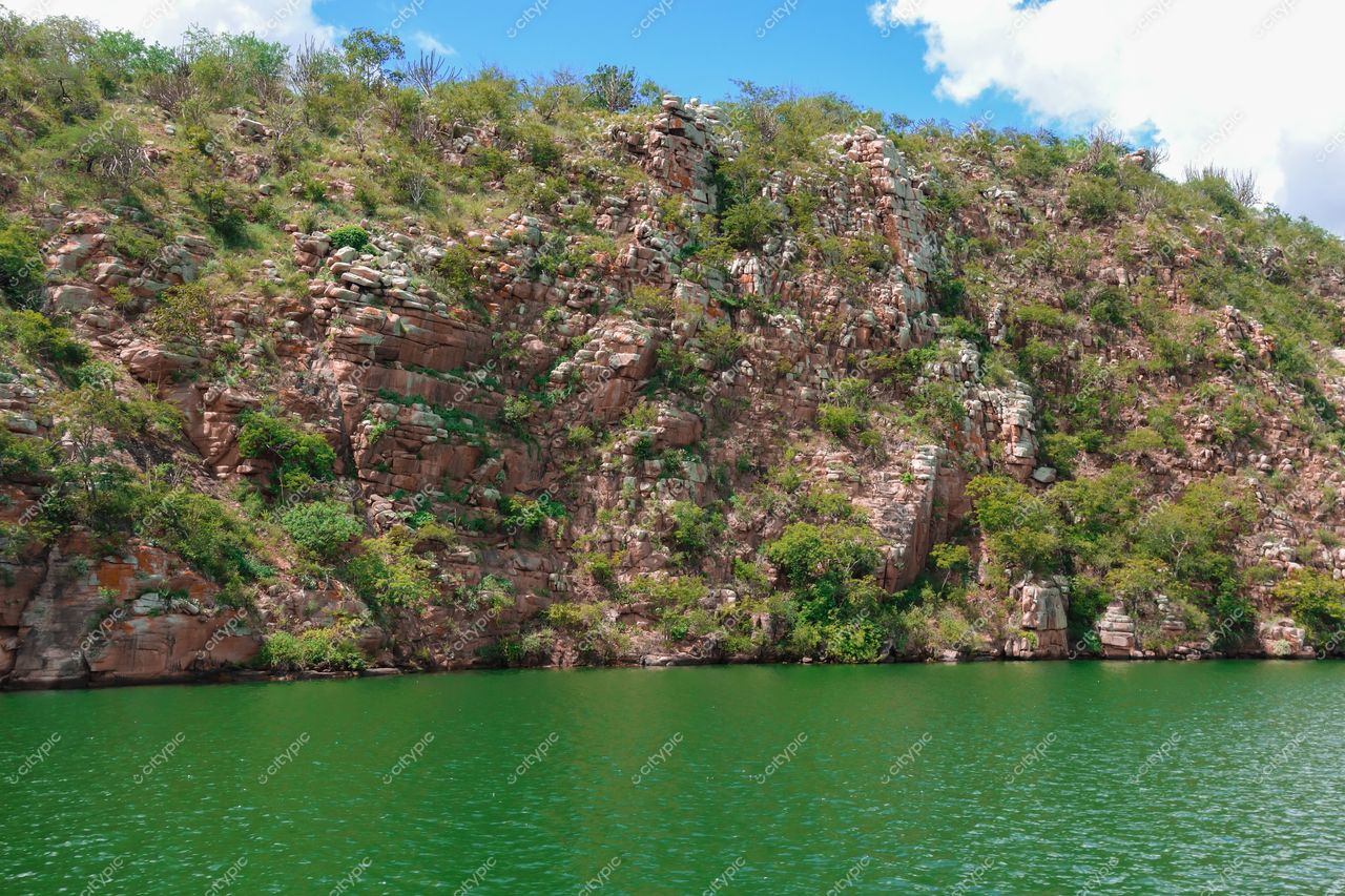 Canindé de São Francisco, Sergipe com rochas avermelhadas e vegetação verde sob céu azul em dia ensolarado