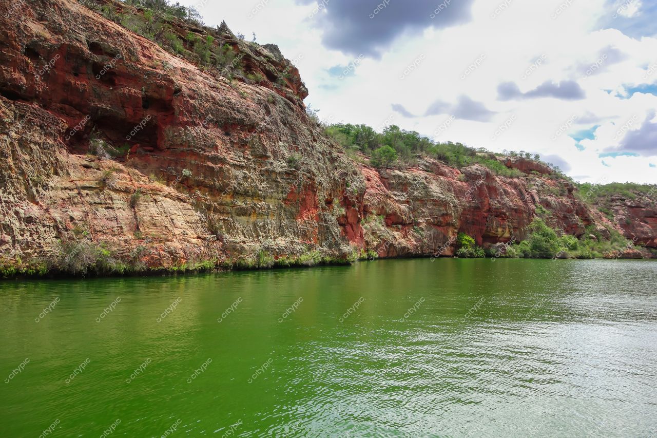 Canindé de São Francisco, Sergipe vista do reservatório com águas verdes e paredões de rocha avermelhados em dia nublado