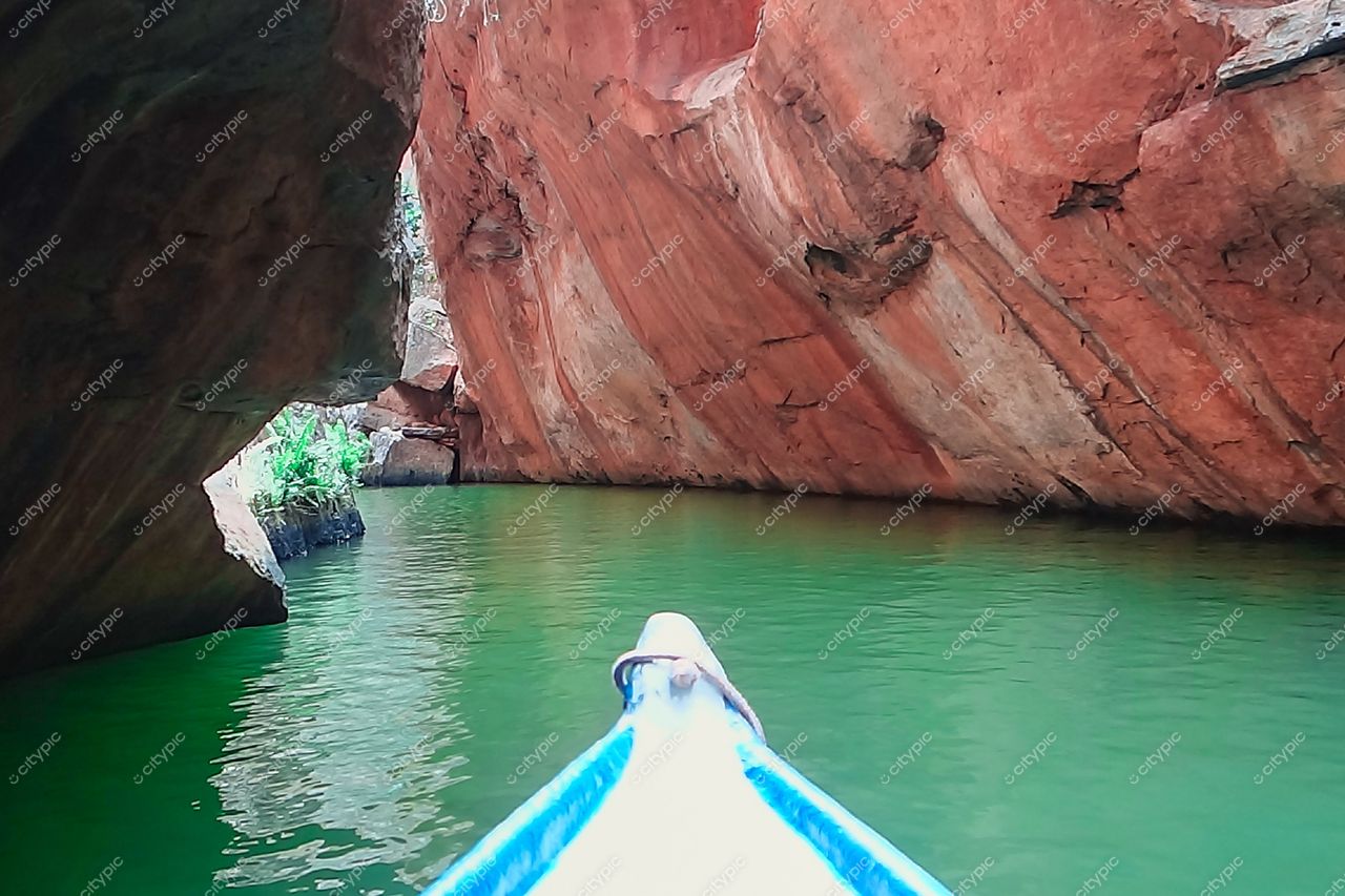 Canindé de São Francisco, Sergipe, canoa flutuando em águas verdes calmas com rochas avermelhadas e vegetação esporádica