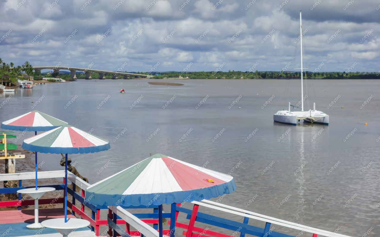 Aracaju, Sergipe vista do Rio Sergipe com guarda-sóis coloridos e catamarã ancorado sob céu nublado