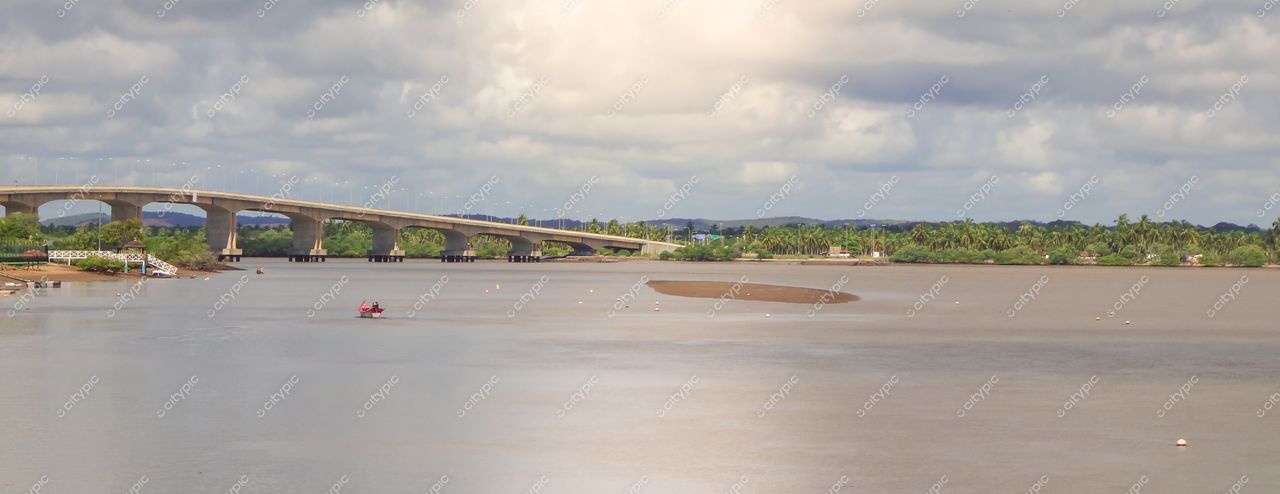 Aracaju, Sergipe com céu nublado e luz suave da manhã refletindo no Rio Sergipe e barco em primeiro plano