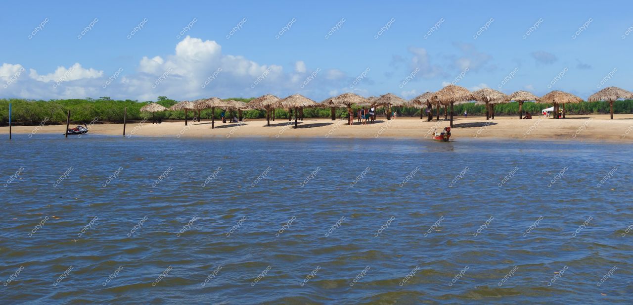 Aracaju, Sergipe, praia com quiosques de palha e mar calmo em dia ensolarado com céu claro e vegetação ao fundo