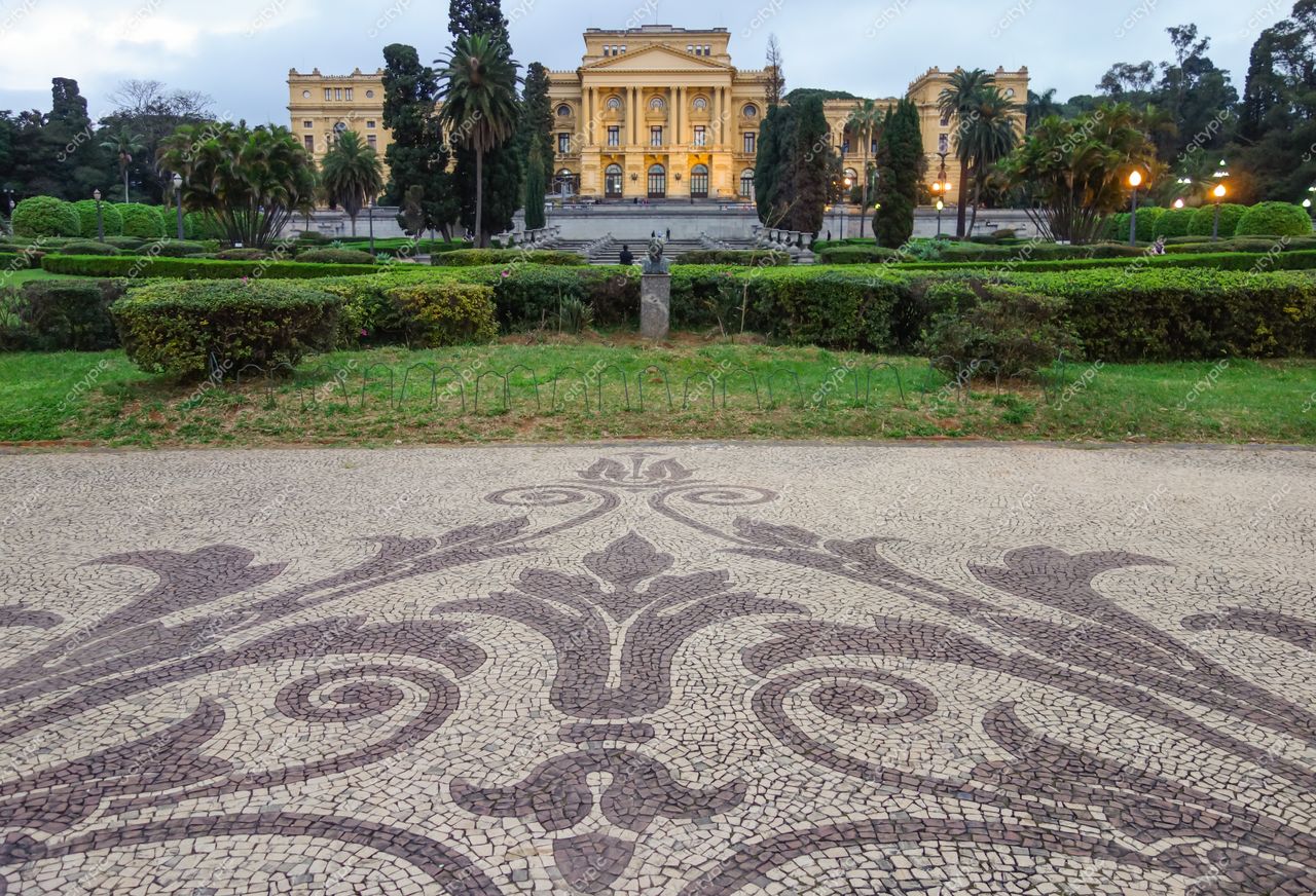 São Paulo, São Paulo vista do jardim em frente a edifício clássico ao entardecer com céu nublado e vegetação cuidada